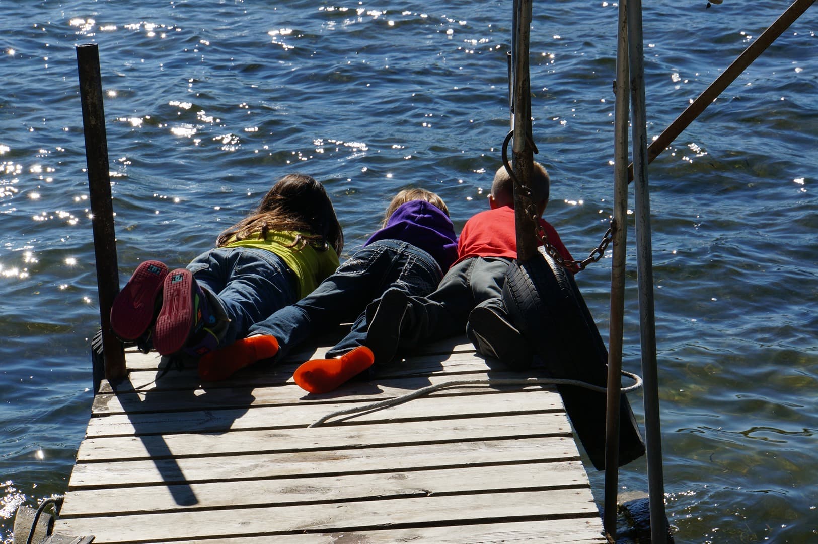 Children taking a closer look at the water from a lakeside dock.